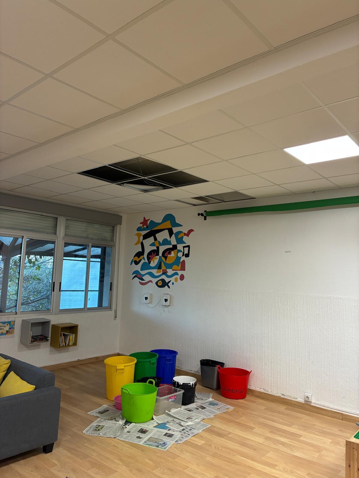 La biblioteca del colegio de Cela, ayer, con cubos y recipientes para recoger el agua por las goteras y filtraciones.