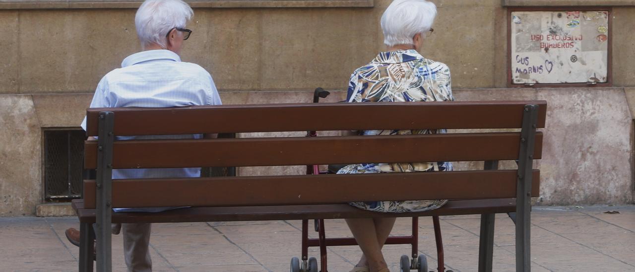 Dos personas de edad avanzada descansan en un banco en la ciudad de Zaragoza.