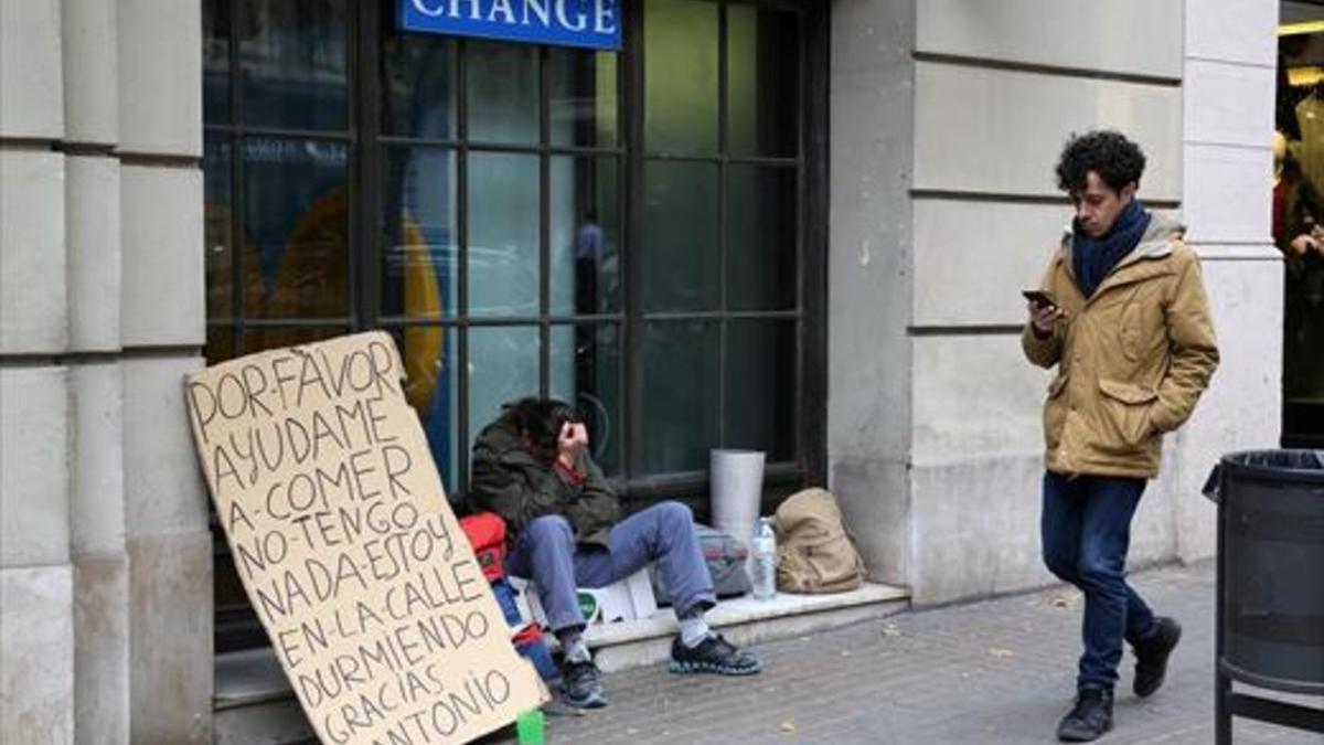 Un hombre sin techo pide ayuda en una calle de Barcelona.