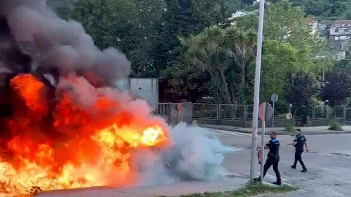 Dos agentes de Policía de Bueu sofocan el incendio de los contenedores.