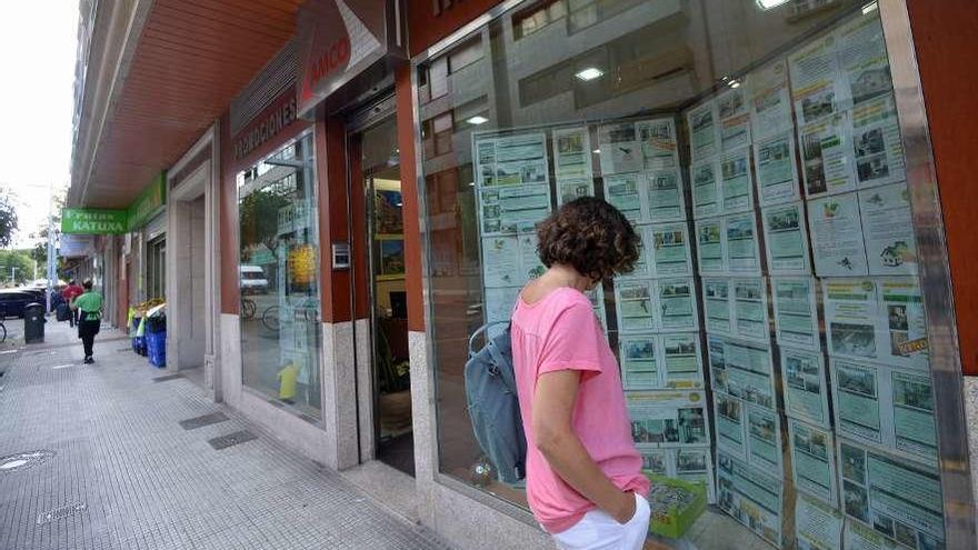 Una mujer observa las ofertas de viviendas en una inmobiliaria.