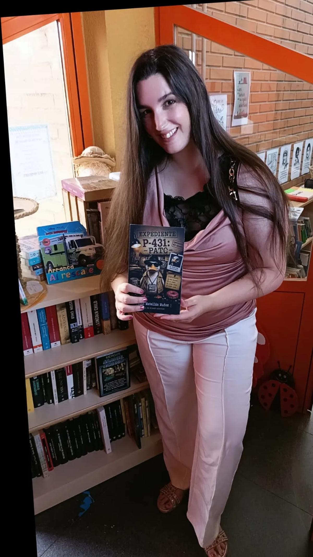 Paqui Matellán muestra la portada de su libro en la biblioteca del colegio.