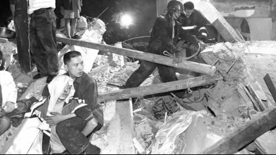 Una pareja asiste a un muchacho atrapado en los escombros tras el terremoto registrado en Sichuan.