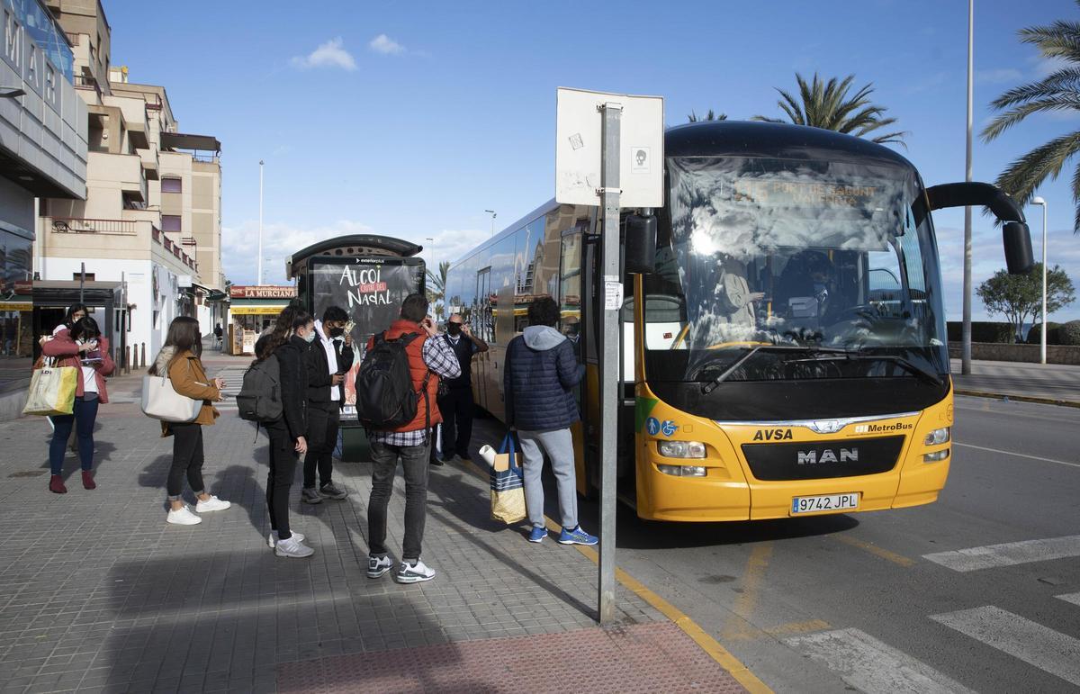 Varias personas al coger el autobús a València en el Port de Sagunt.