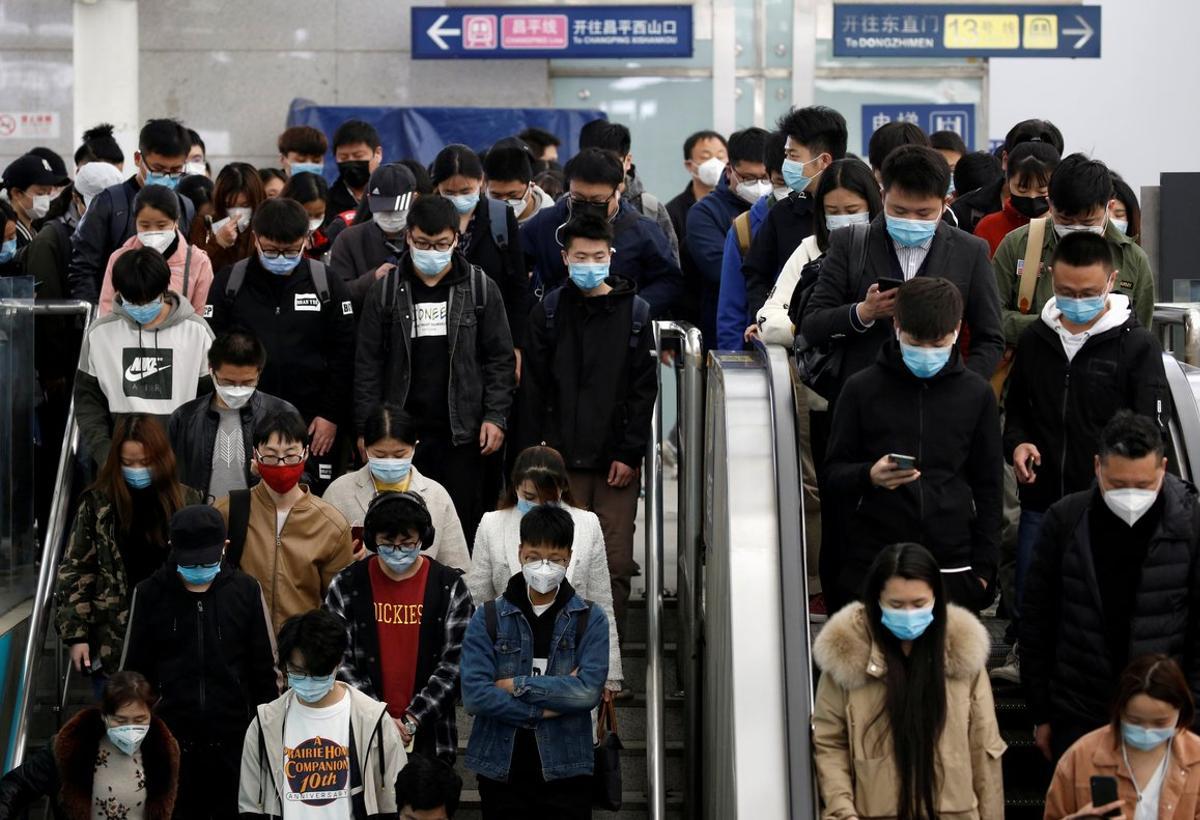 People wearing face masks stand on an escalator inside a subway station during morning rush hour in Beijing, as the spread of the novel coronavirus disease (COVID-19) continues in the country, in China April 7, 2020. REUTERS/Tingshu Wang REFILE - CORRECTING DESCRIPTION OF ESCALATOR