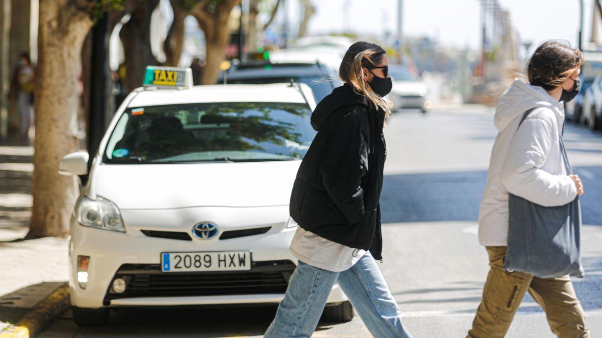Dos personas cruzan por delante de una de las paradas de taxi de Ibiza, ayer.