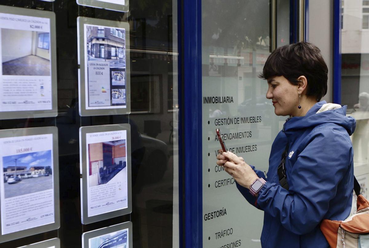 Una mujer mirando anuncios de pisos en una inmobiliaria de la avenida de la Argentina.
