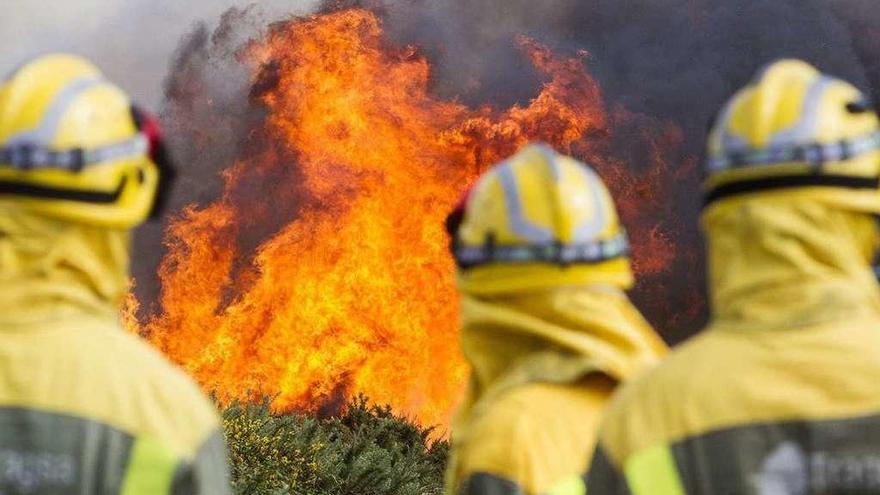 Efectivos antiincendios ante las llamas de un fuego en las proximidades de Santiago.