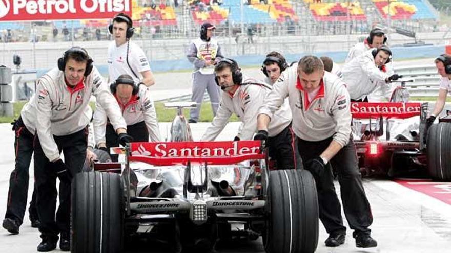 Los mecánicos de McLaren empujan el coche de Hamilton durante unos entrenamientos.