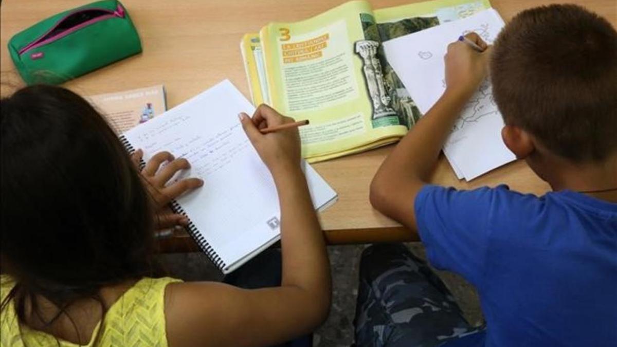 Una niña y un niño hacen las tareas en el colegio, en una imagen de archivo.
