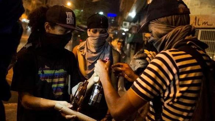 Jóvenes opositores a Maduro preparan cócteles molotov.  // Efe