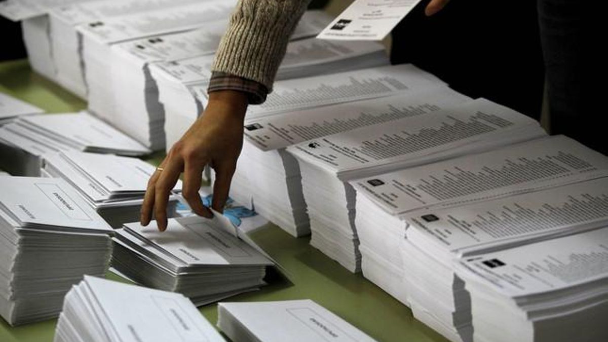 Una persona coge una papeleta de voto en un colegio electoral de Madrid.