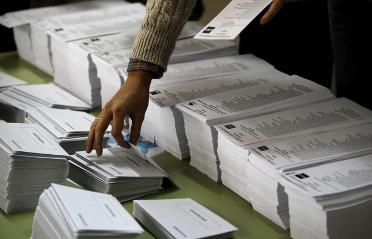 Una persona agafa una papereta de vot en un col·legi electoral de Madrid.