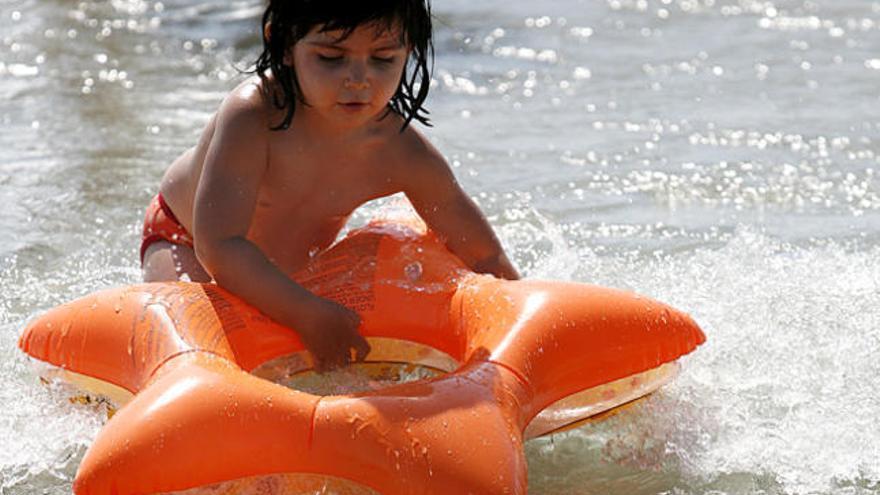 Una niña usa un flotador en la playa.