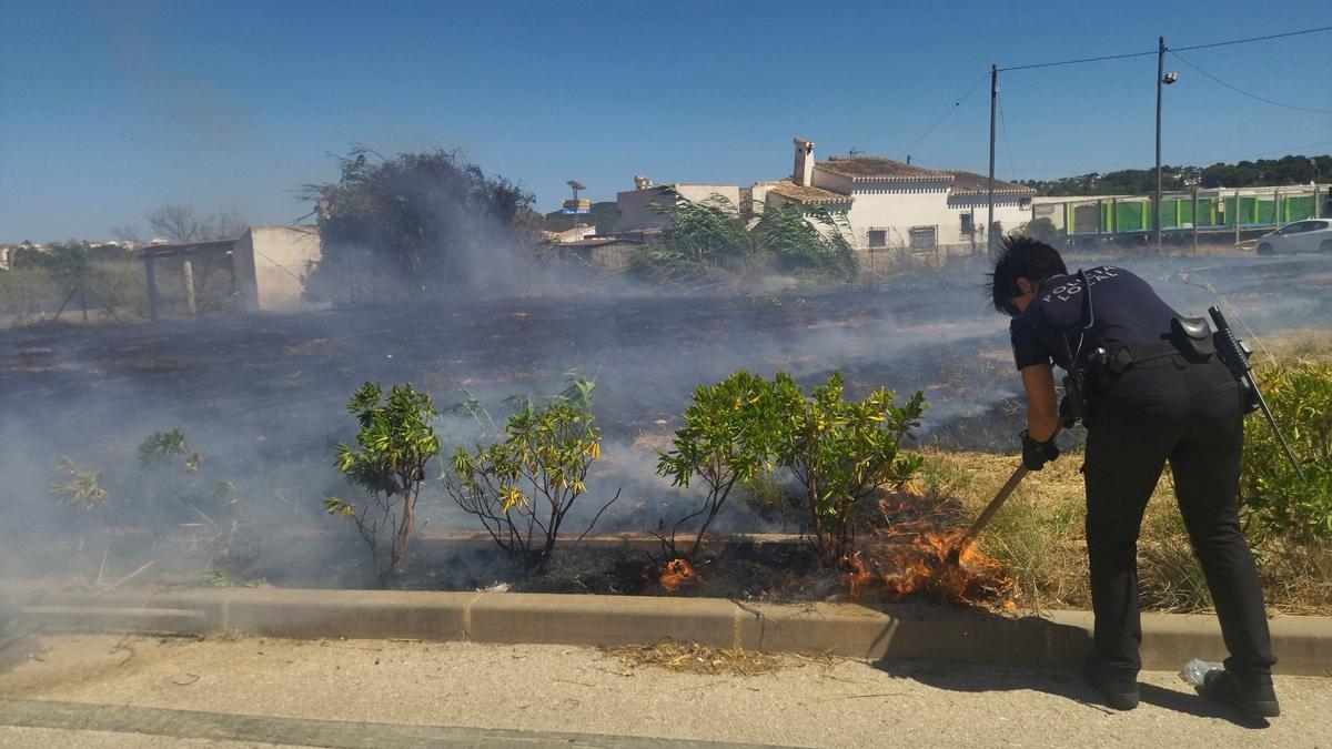 Una agente de la Policía Local sofoca las llamas con una azada