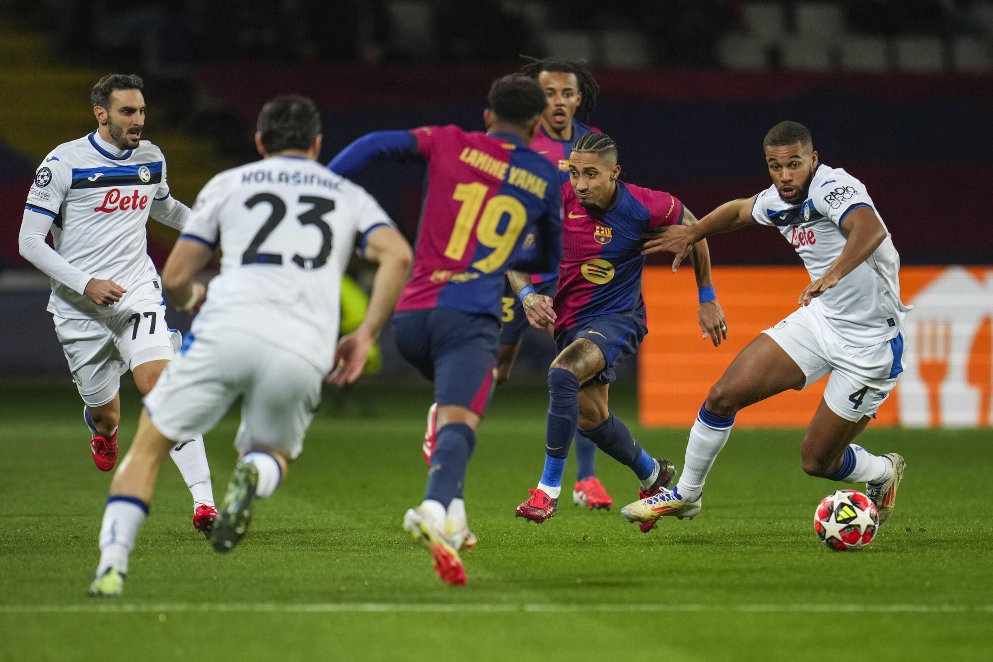 Atalanta's Isak Hien, right, runs with the ball next to Barcelona's Raphinha, second right, during a Champions League opening phase soccer between Barcelona and Atalanta match at the Lluis Companys Olympic stadium in Barcelona, Spain, Wednesday, Jan. 29, 2025. (AP Photo/Emilio Morenatti). EDITORIAL USE ONLY / ONLY ITALY AND SPAIN