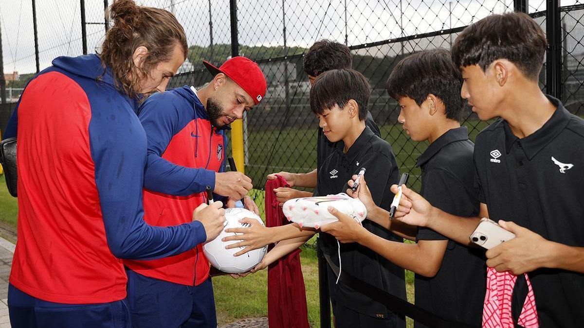 Memphis Depay y Çağlar Söyüncü firman autógrafos en el ’stage’ del Atlético en Corea del Sur.