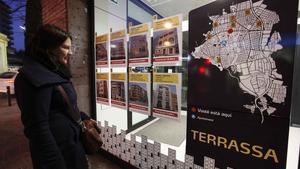 Una mujer mira precios de pisos en una inmobiliaria de Terrassa.