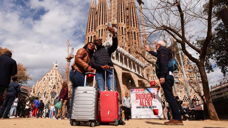 Turistas se toman un selfie junto a un cartel en la Basílica de la Sagrada Familia de Barcelona