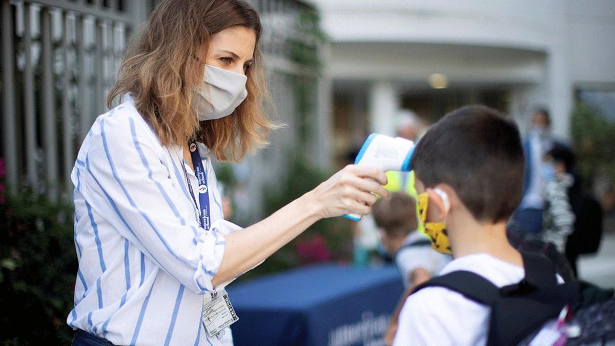 Una trabajadora toma la temperatura a un niño a la entrada del colegio privado internacional American School of Barcelona, en Esplugues de Llobregat (Barcelona), el lunes 1 de septiembre