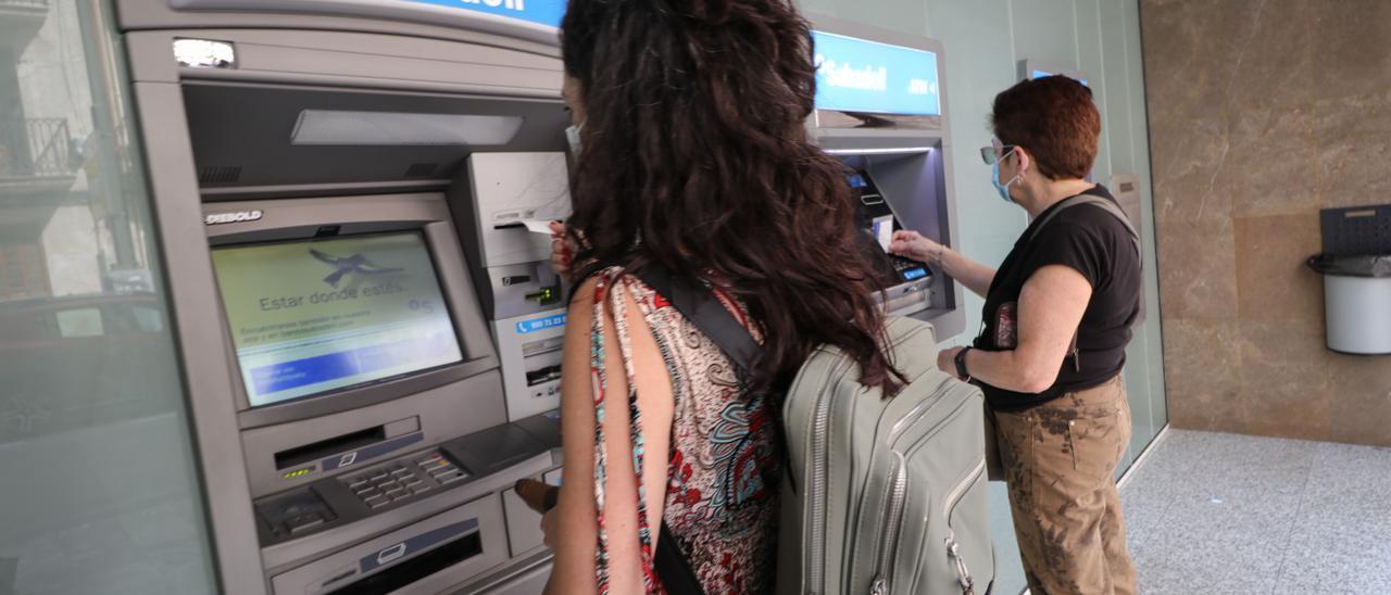 Clientes en los cajeros automáticos del Banco Sabadell.