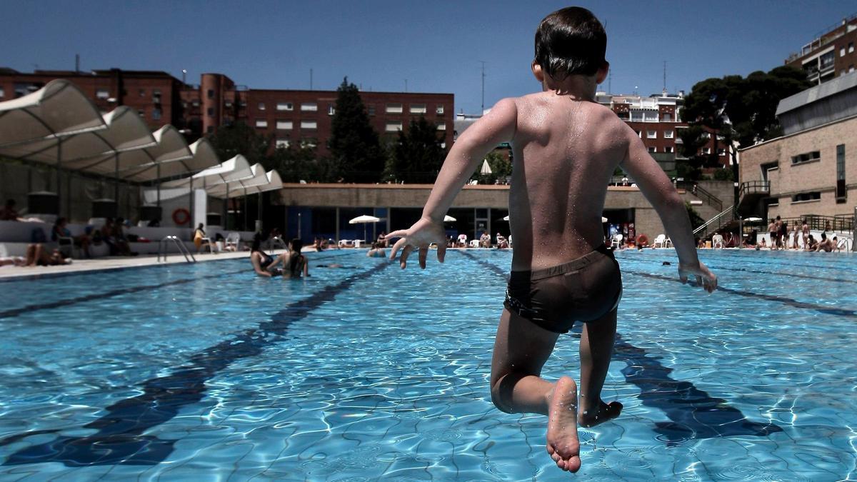 Un niño se lanza a la piscina.