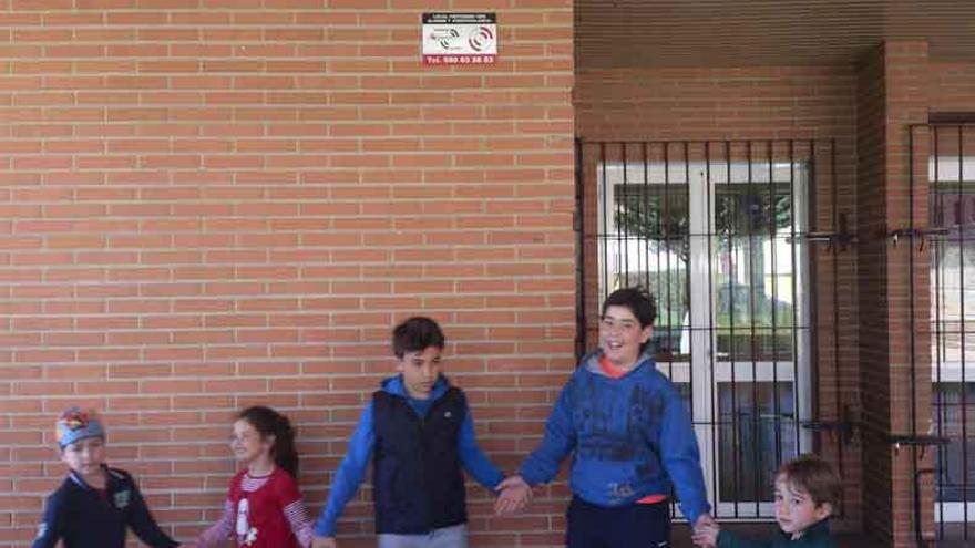 Niños de &quot;Vacaciones en el Cole&quot; juegan ayer en El Pinar bajo el cartel que advierte de la seguridad.