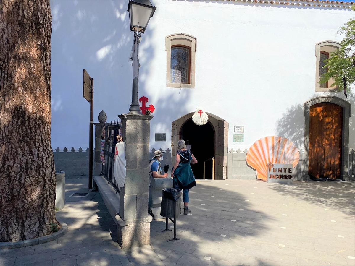 Una pareja de peregrinos a las puertas de la iglesia de San Bartolomé en Tunte.