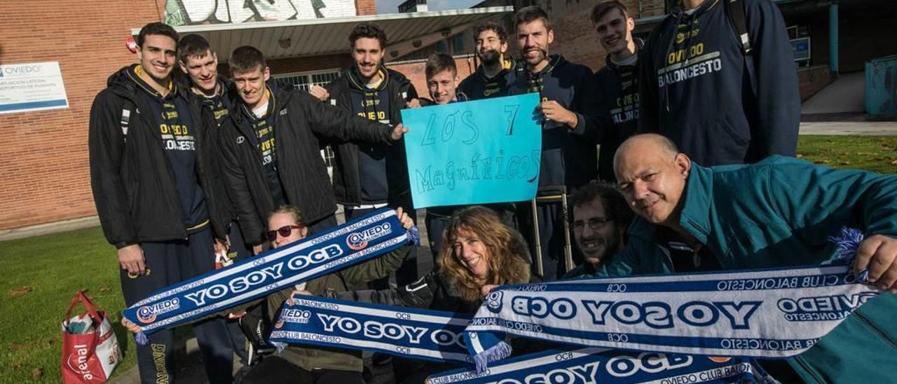 Aficionados del Oviedo Baloncesto posan con los nueve jugadores que se desplazaron a Lérida, incluidos Davis Geks y Jorge Sanz (con la cartulina de &quot;Los 7 Magníficos&quot;), que no pudieron jugar por cuestiones burocráticas.