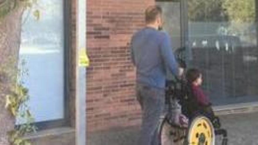 El pare, amb el fill en cadira de rodes, a l´aparcament.
