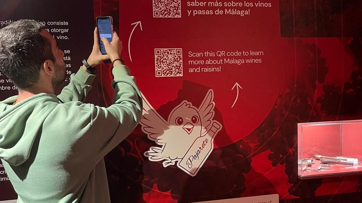 Un usuario en el Museo del Vino de Málaga escanea con su móvil el QR para hablar con 'Pajarete', el asistente virtual desarrollado con IA