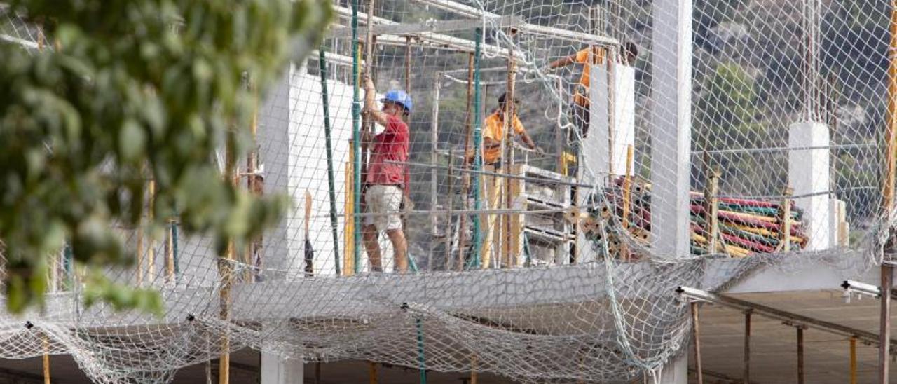 Operarios trabajando en la construcción de un edificio de viviendas en Xàtiva, ayer. | PERALES IBORRA