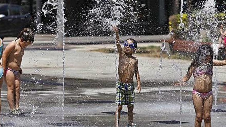 Un grup de nens aprofitant per refrescar-se i jugar amb unes fonts a Platja d&#039;Aro.