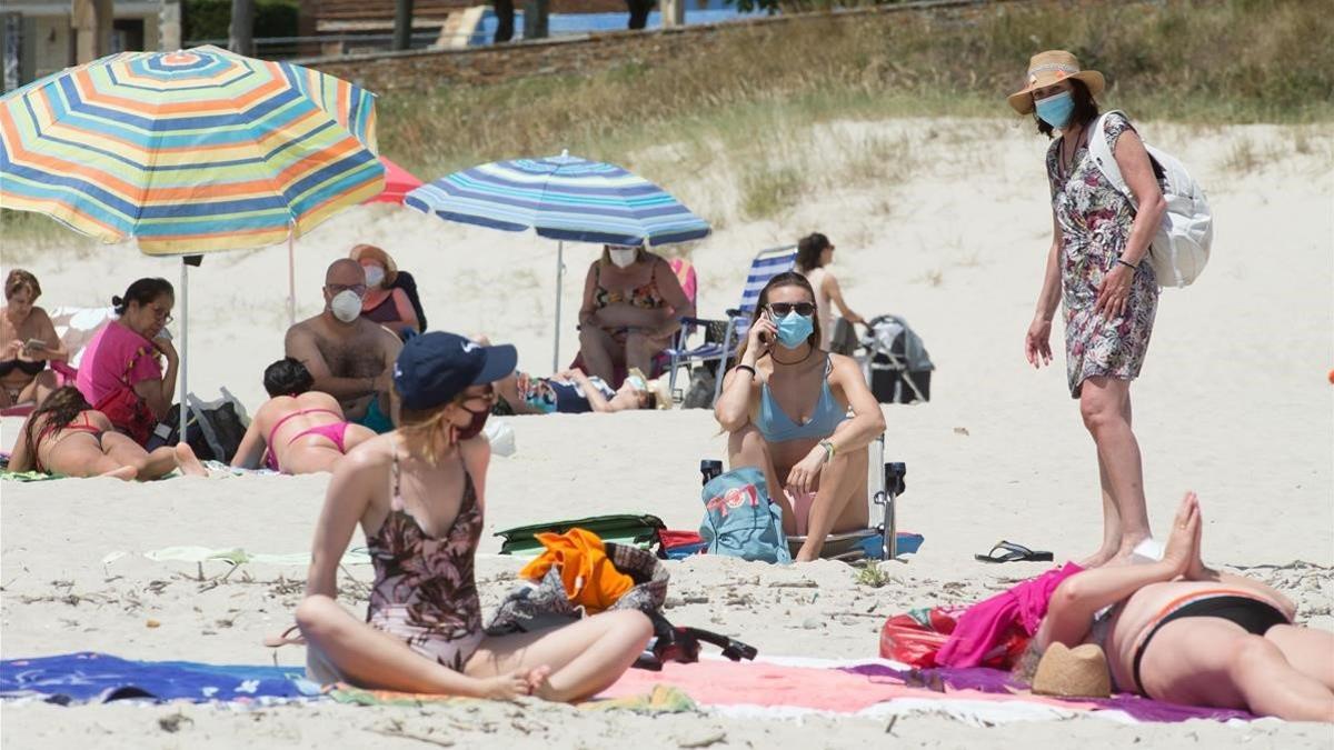 Personas protegidas con mascarillas en la playa de A Rapadoira, en Foz, en la comarca de A Marina (Lugo), el 9 de julio del 2020