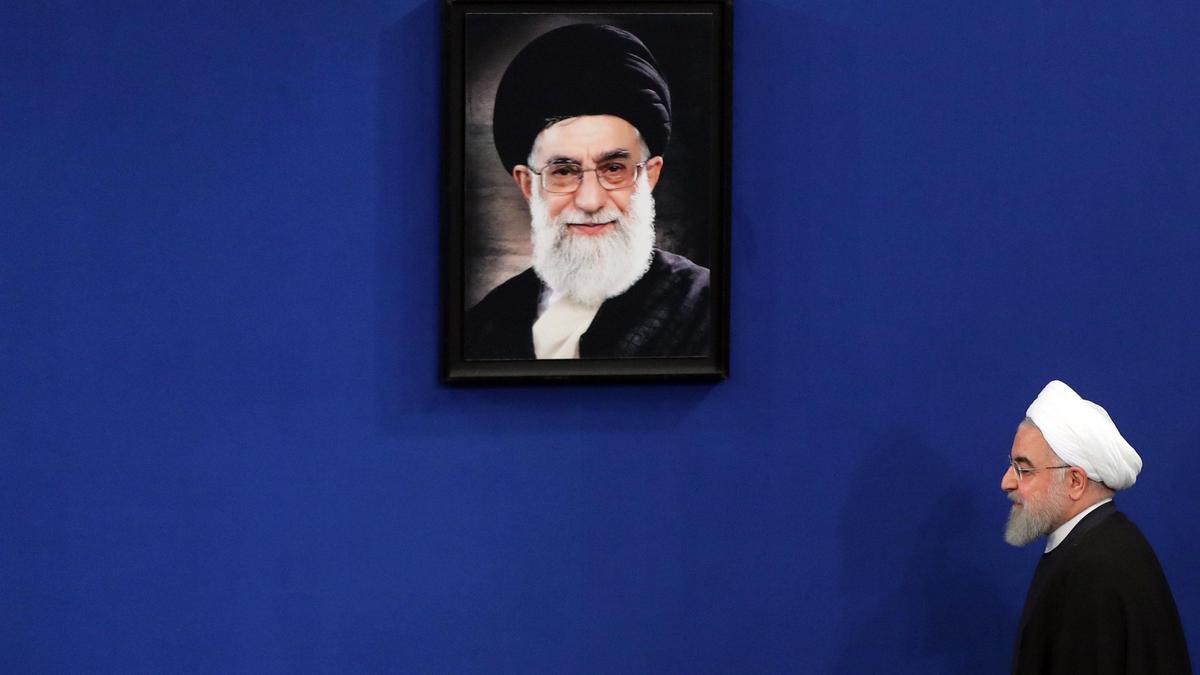 Hassan Rouhani camina junto a retrato de Ali Jamenei