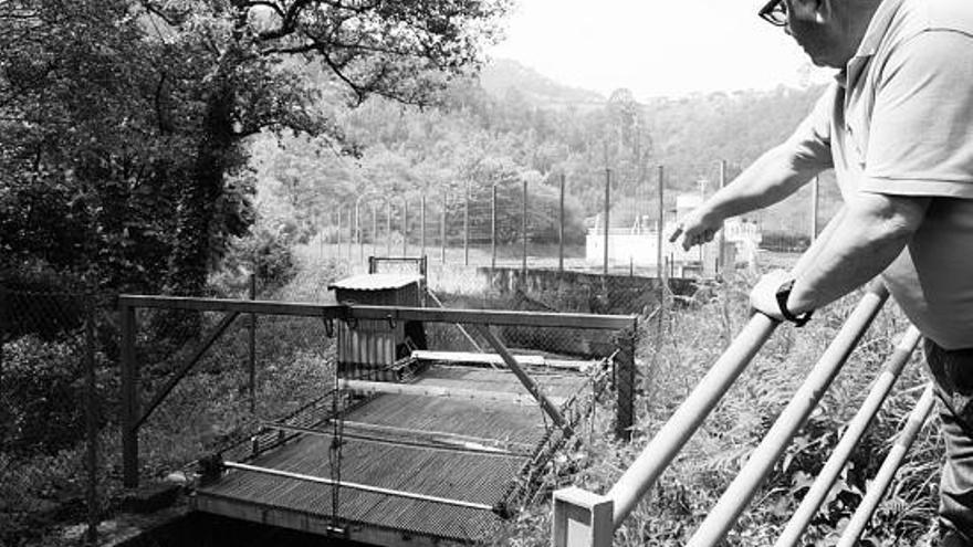 Alberto Fernández señala la reja, abierta, que comunica el río con la piscifactoría, en Canero.