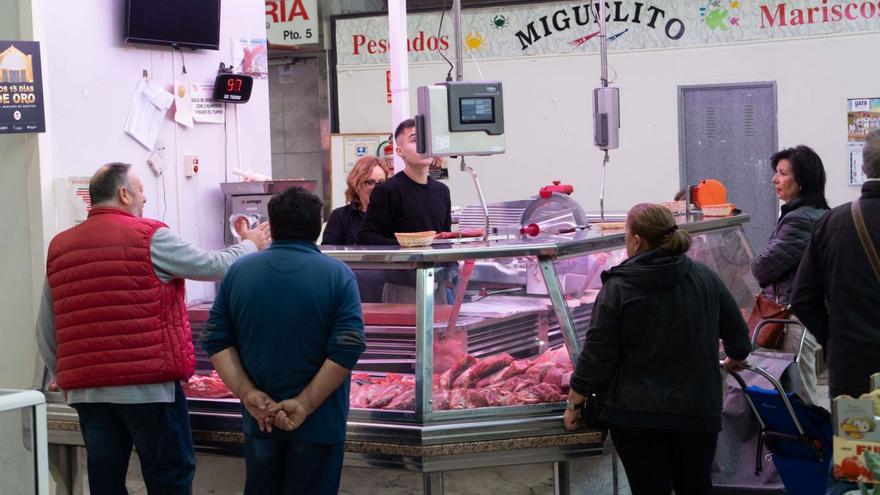 Varias personas comprando en un puesto en el Mercado de Abastos de Zamora.