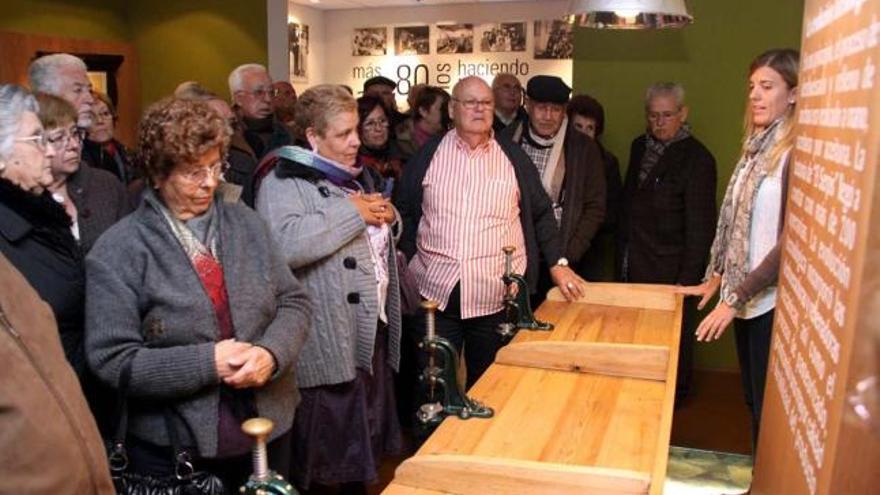 Un grupo de visitantes observa cómo funcionaba una deshuesadora de los años 20.