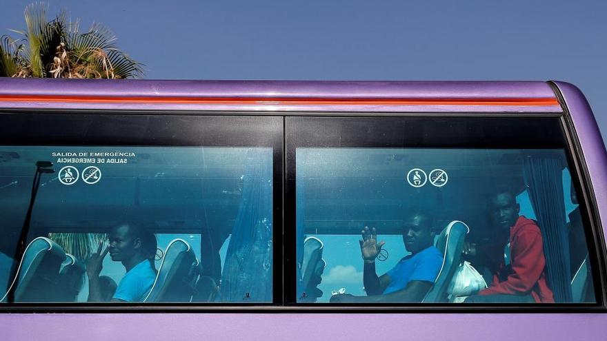 Algunos de los migrantes saludan desde el autobús esta mañana.