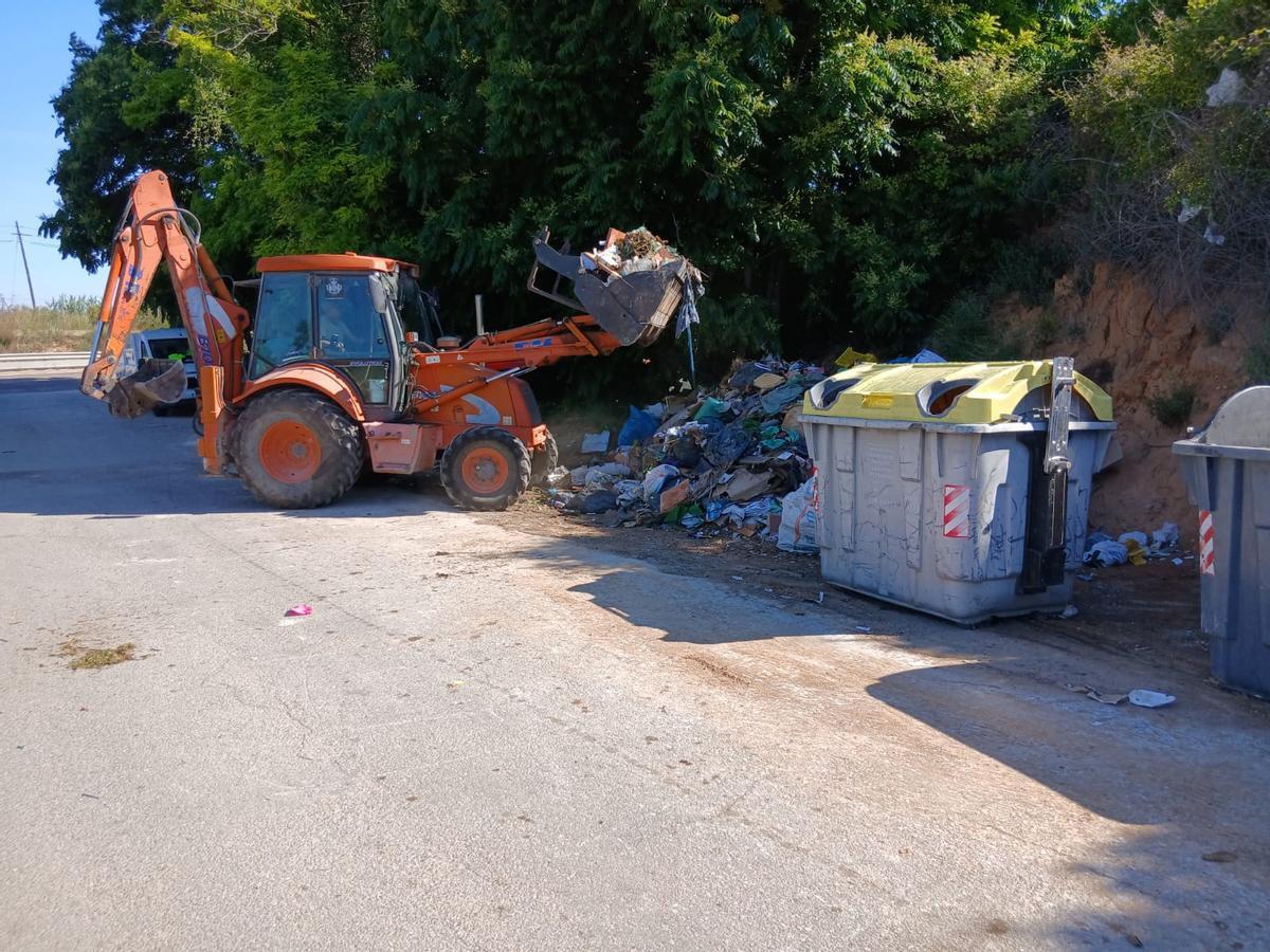 Un tractor recoge la basura junto a los contenedores.