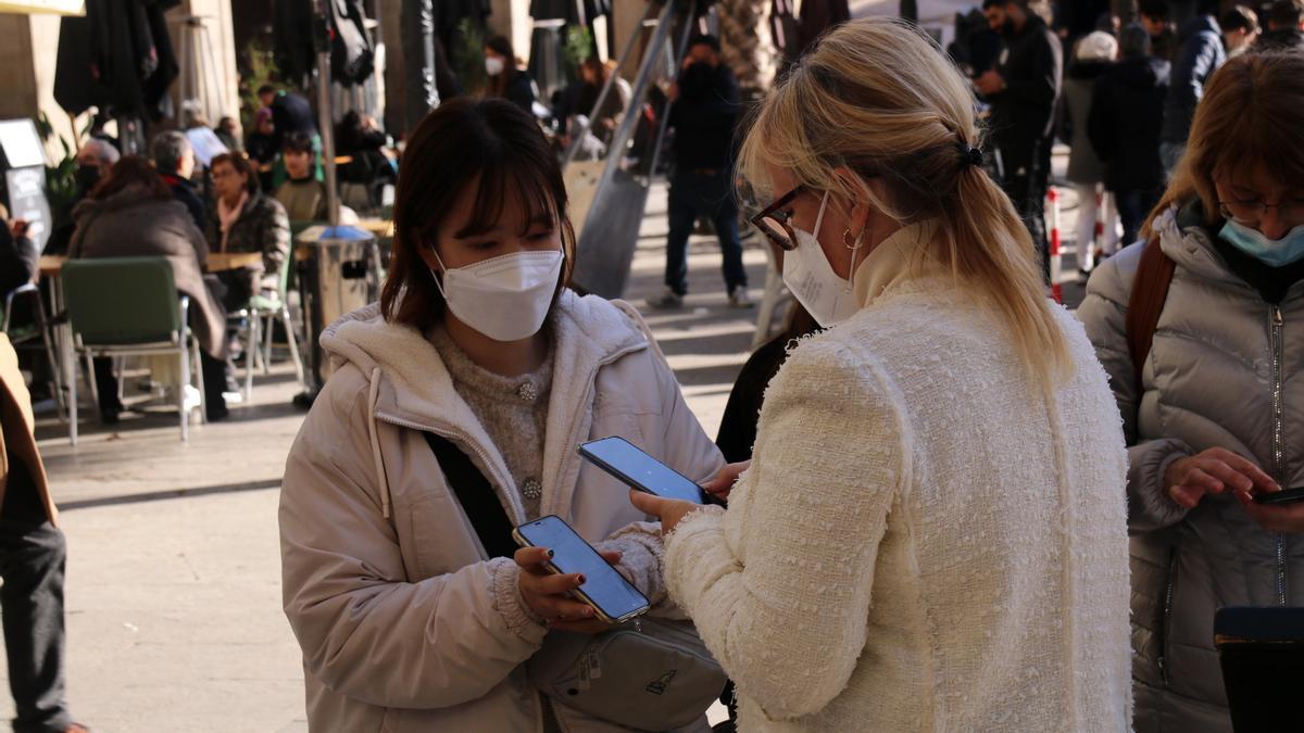 Una clienta ensenyant el certificat covid a una treballadora d&#039;un restaurant de la plaça Reial de Barcelona