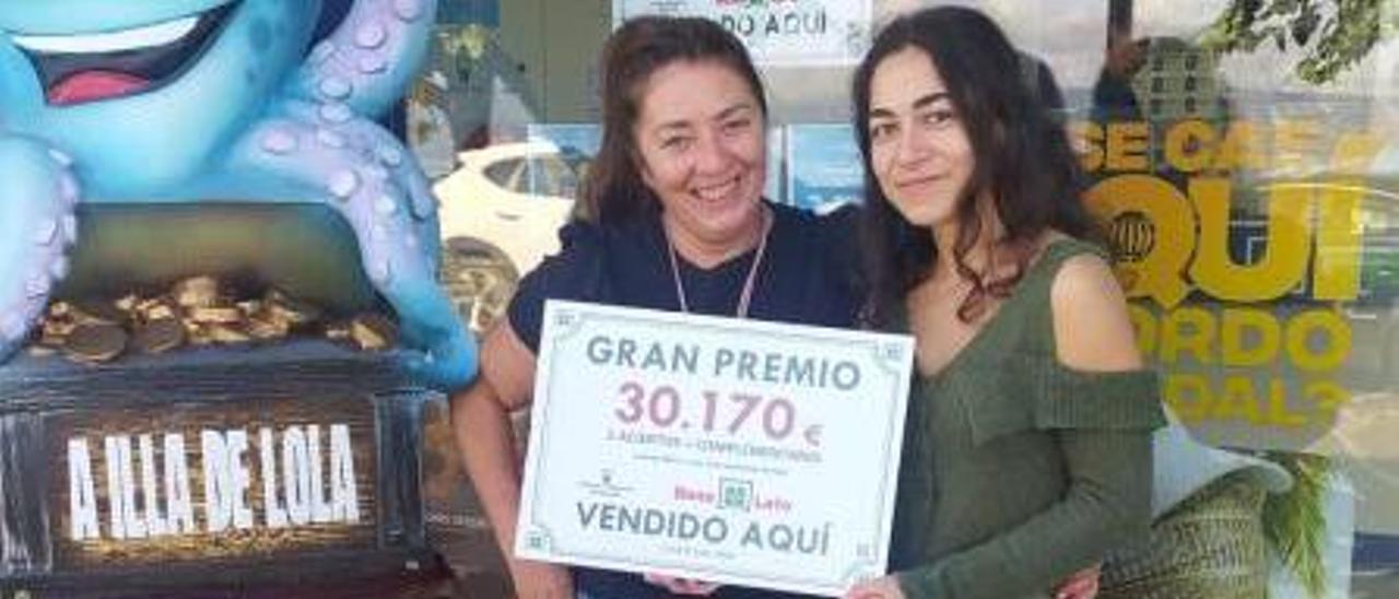 Dos de las empleadas de la administración de lotería de Bueu con el cartel del premio de la Bonoloto.   | // Fdv