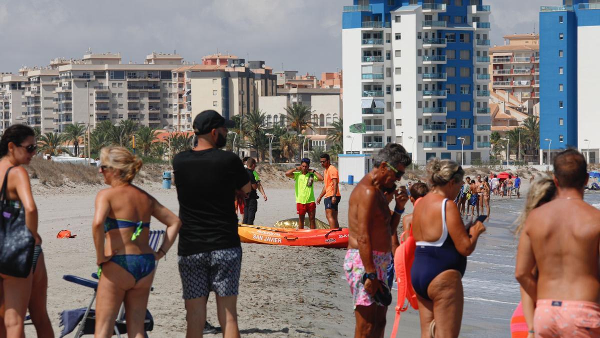 Bañistas de la zona observan el cadáver sobre la arena de La Manga.