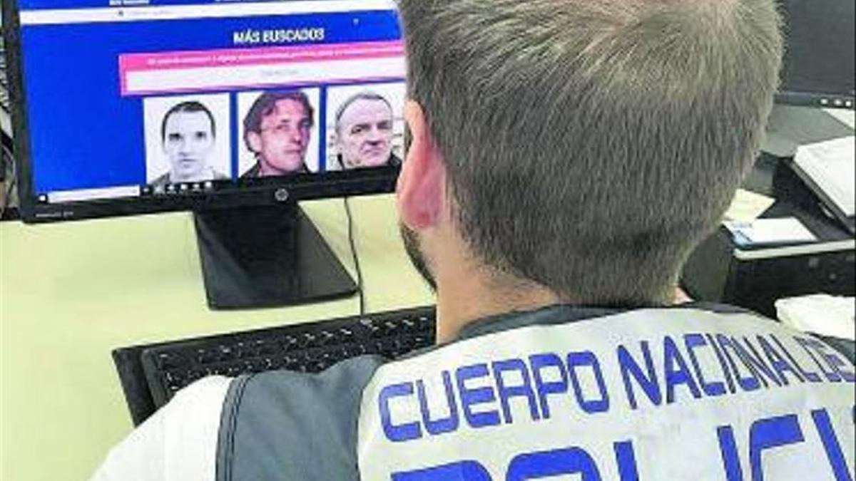 Un policía nacional muestra algunos de los prófugos más buscados.