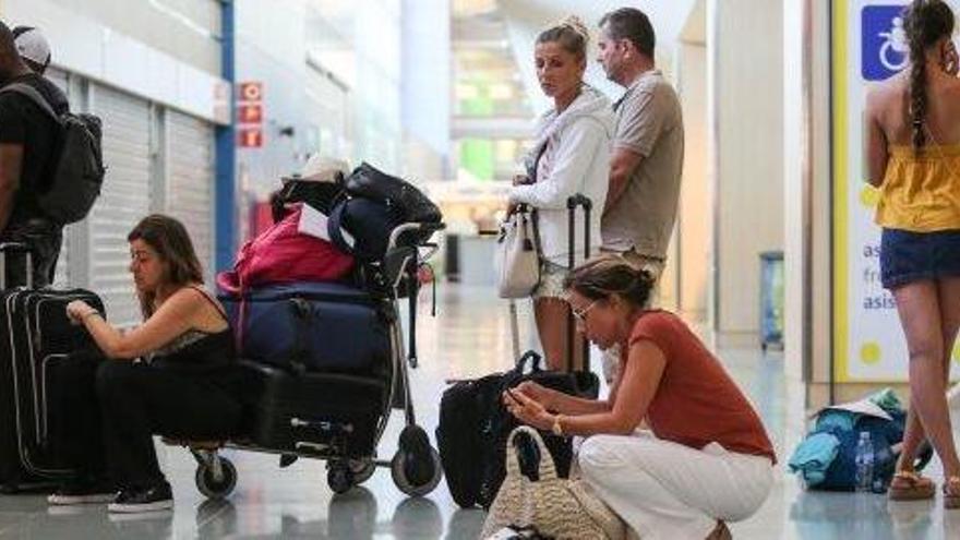 Turistas esperan en la terminal de Ibiza uno de los vuelos que partieron ayer de la isla.