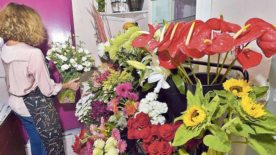 Una floristera coloca flores en el expositor de su establecimiento.