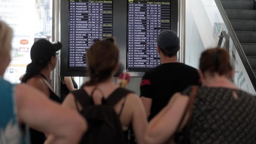 Pasajeros en el aeropuerto de Palma pendientes del panel informativo de vuelos. | MANU MIELNIEZUK