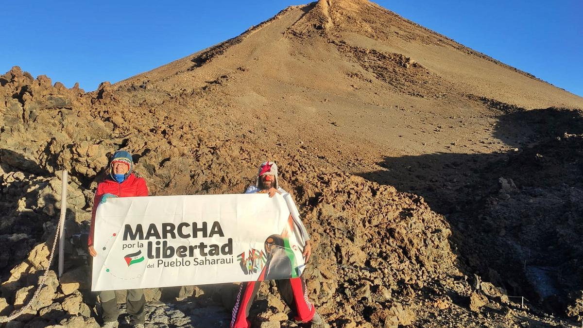 A la izquierda, el cartel de la iniciativa, con el pico detrás, sostenido por los protagonistas, Arriba, Iván