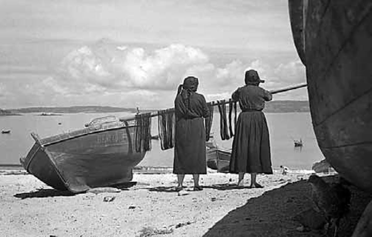 Dúas mulleres traballando na reparación de redes de pesca.