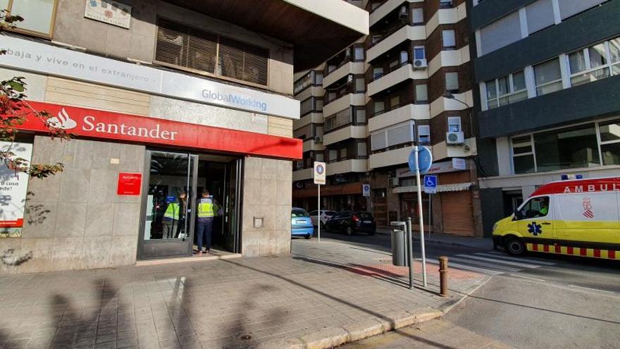 La Policía Nacional y la ambulancia que evacuó al herido ayer en la sucursal atracada.